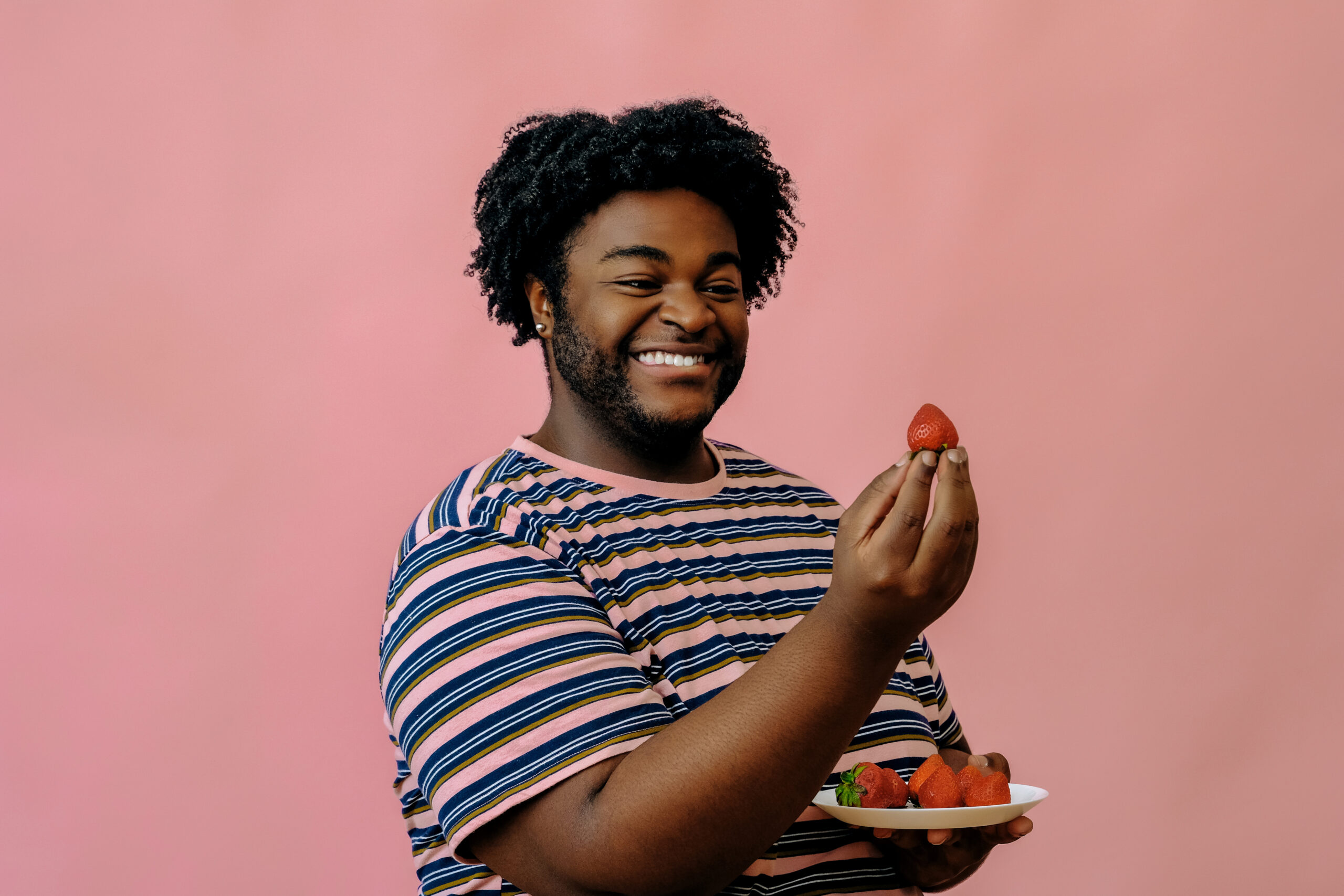Young man holding a strawberry and smiling