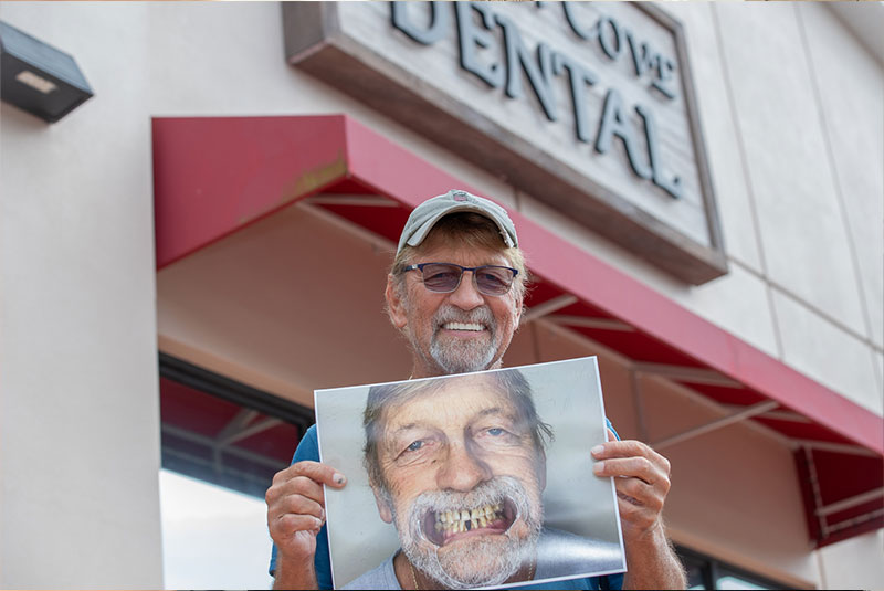 patient smiling and holding up their before procedure img outside of the dental practice